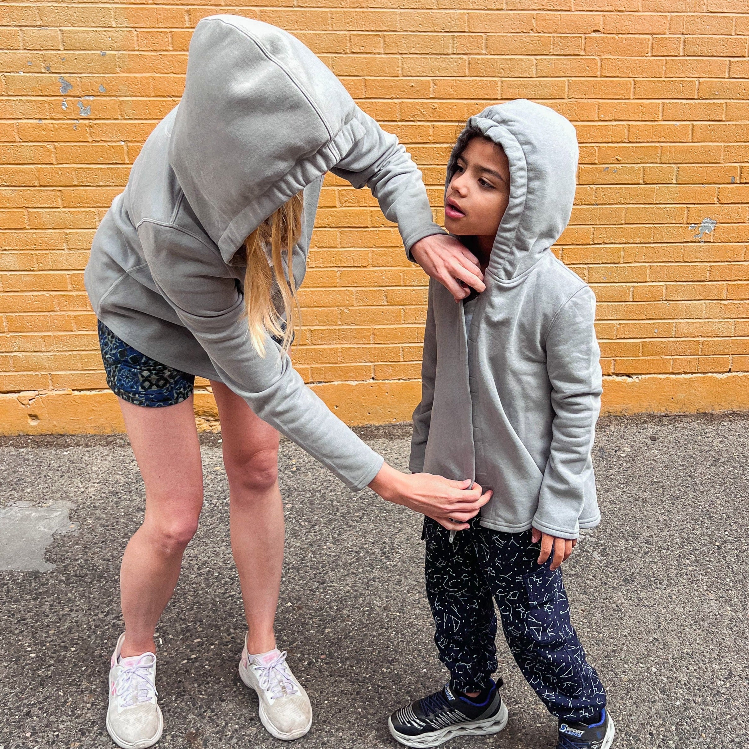 Adult helping autistic child with magnetic closure on sensory hoodie