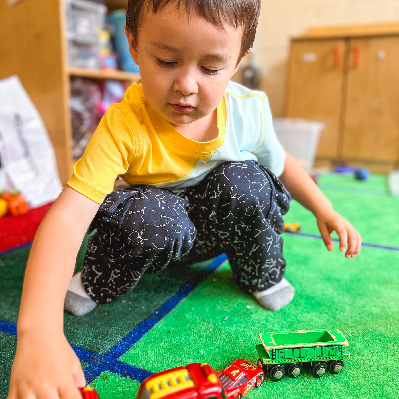 autistic child playing with train set in special education classroom while wearing sensory friendly clothing
